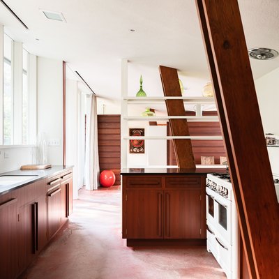 Mid-century kitchen with white walls, building-in shelving, wood cabinets and beams