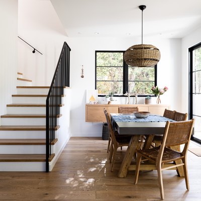 Dining room with white walls, wood furniture and flooring with staircase