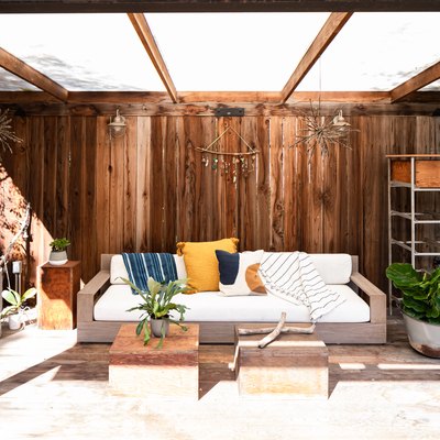 Outdoor storage and organization idea under wood pergola with sofa, plants, and shelving