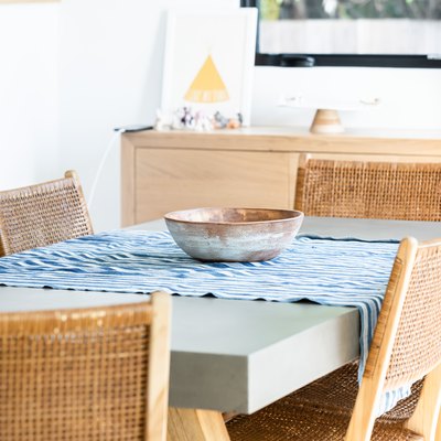 Dining table with table runner and bowl with wicker chairs