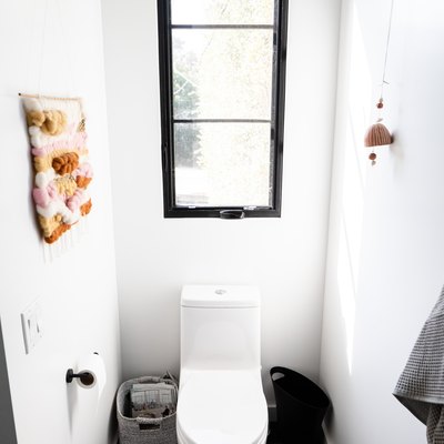 White-walled bathroom with a long black framed window over a toilet