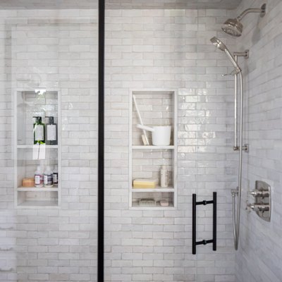 Glass door shower with gray wall tiles and shower niches