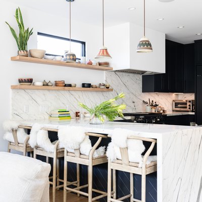 White walled kitchen with granite counters, white chairs, and dark gray cabinets