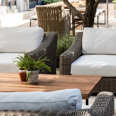 White cushioned patio chairs with a wood coffee table and plants.