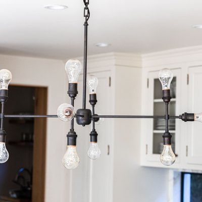 A contemporary industrial light fixture in a white cabinet kitchen