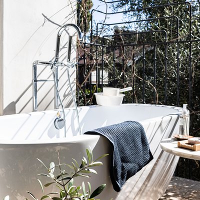 A bathtub on a balcony surrounded by plants.