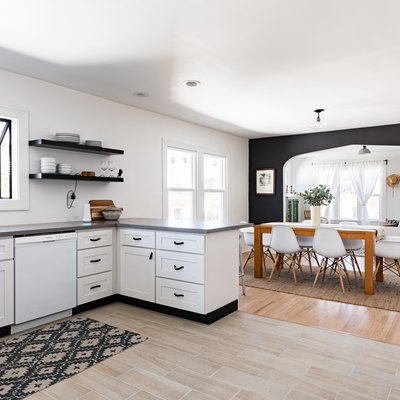 A white kitchen with white-black cabinets and a dining room with wood floors