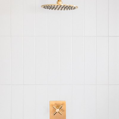 Gold shower head and white tile wall