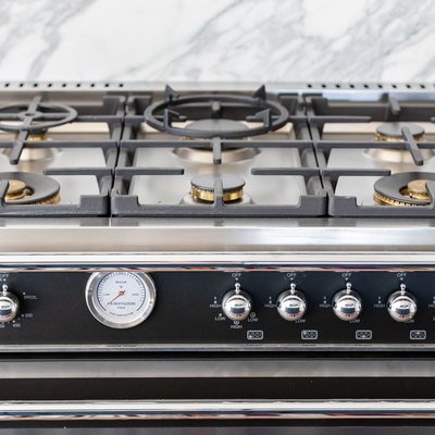 A stovetop with a gray-white granite backsplash