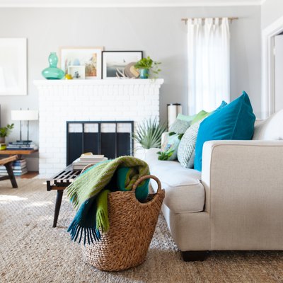 Boho-beach living room with a white brick fireplace, wood furniture, turquoise and green decor, and woven accents.