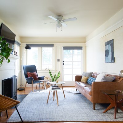 a living room with a leather couch, mid-century side tables, and a lamp with a glass globe for a shade