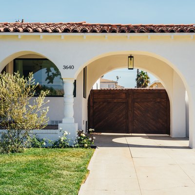 Spanish house, front yard, lawn, driveway, arched entry, wood gate.