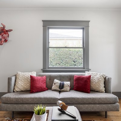 Living room with a gray furniture and window frames, red and white pillows, and contemporary decor