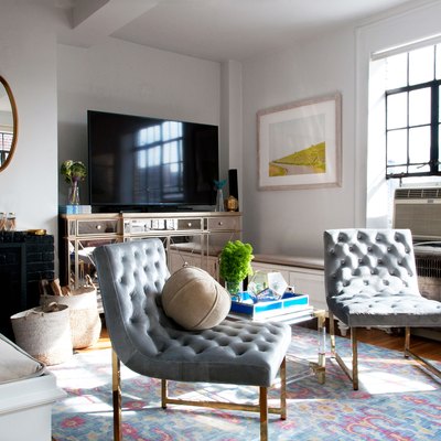 Two mid-century gray upholstered chairs sit on a colorful pastel rug in the living room.