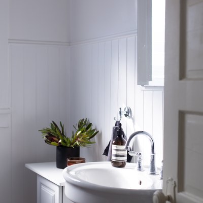 walls, wainscotting, sink, and vanity are all white in this bathroom