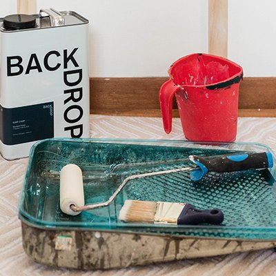 Paint tray, paint brush, paint roller, container of paint, and a paint bucket