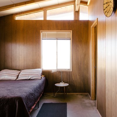 a bedroom with a modern sloping ceiling and retro wood paneling on the walls