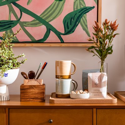 Wood cabinet with flowers and coffee station against pale pink wall