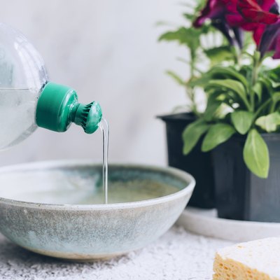 mixing water and dish soap in a ceramic bowl