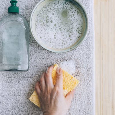 using a sponge and a solution of dish soap and water to clean carpet stain