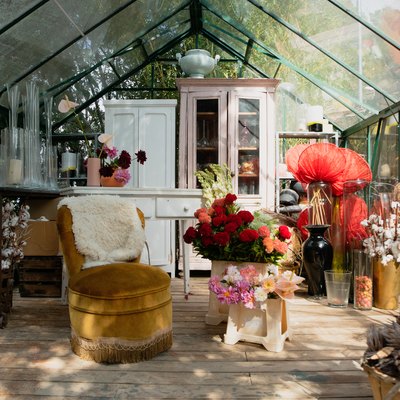 Greenhouse with mismatched, shabby chic furniture, plants and vases
