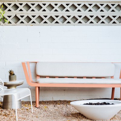 a pink bench with mid-century lines on gravel in front of a cone-shaped fire pit