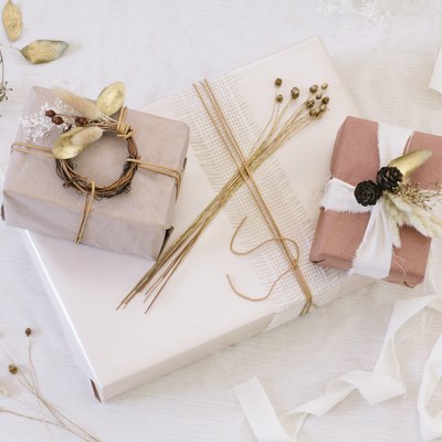 Packages with brown, white, and neutral paper with white ribbon and dried flowers