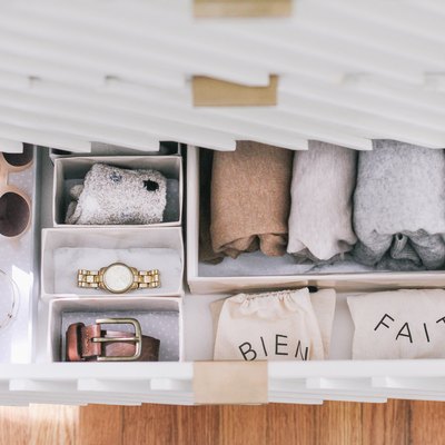 Wrapped sheets, ties, and sunglasses in DIY hikidashi boxes in open drawer of contemporary cabinet against wood flooring