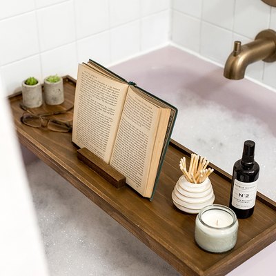 Wood bath tray with reading glasses, book, plants over bathtub