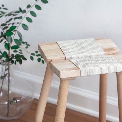 Wood stool with rope next to clear vase with plant