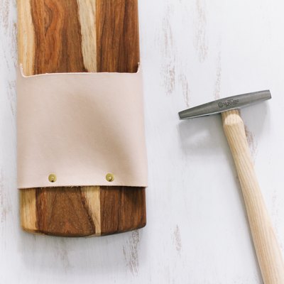 a tack hammer and a cutting board with leather strips attached with tacks