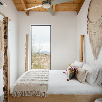 Minimalist bedroom with boho wall hangings and a rectangular window