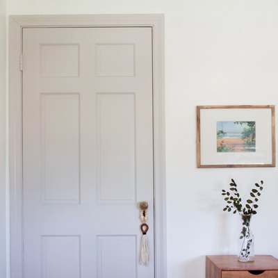 White door and white walls with framed art and side table to plant in vase