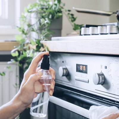 using spray bottle to clean a stainless steel oven with water and rubbing alcohol