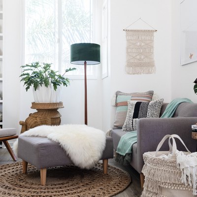 Gray-white furniture in a living room with plants and Boho decor.