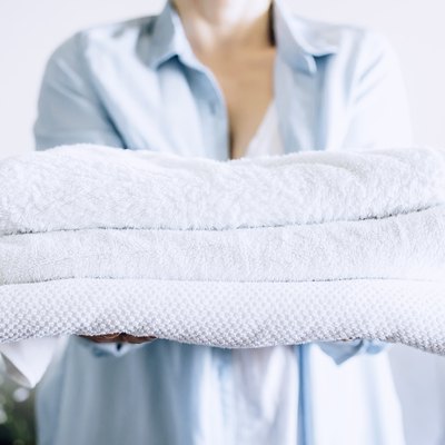 A woman holding a stack of freshly cleaned white towels