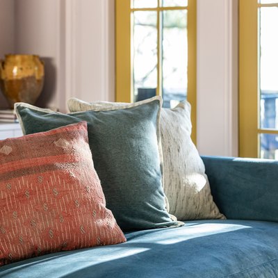 Throw pillows on a blue couch, and yellow French doors.