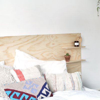 a headboard made out of a sheet of unfinished plywood with two shelves mounted on it