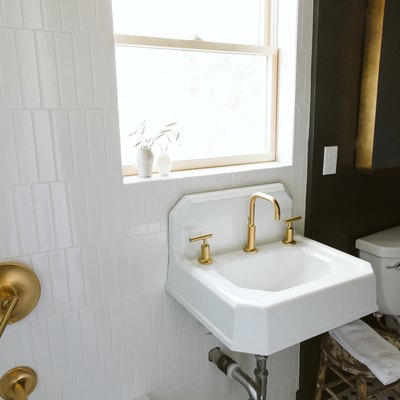 sink with a gold faucet and black wall in a bathroom