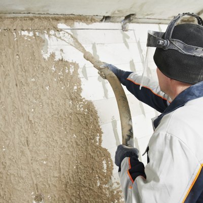 Plasterer at stucco work with liquid plaster