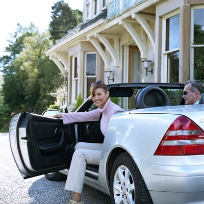 Woman stepping out of car in driveway, smiling, portrait