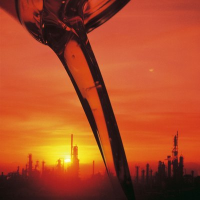 Oil pouring from a container , image of refinery background