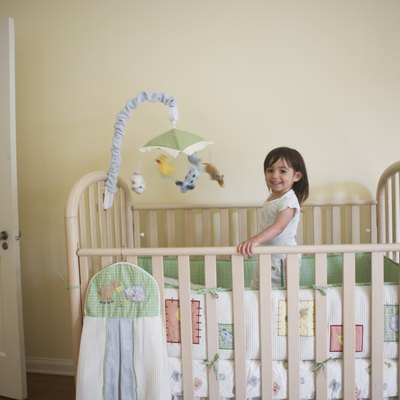 Toddler girl standing in her bedroom crib