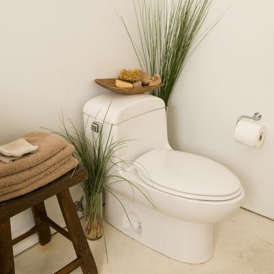 Corner of bathroom with toilet and towels on stool