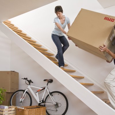 Couple carrying heavy moving box up stairs