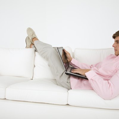 Man lying on sofa with laptop computer