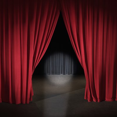 Empty stage with curtains slightly open and spotlight on