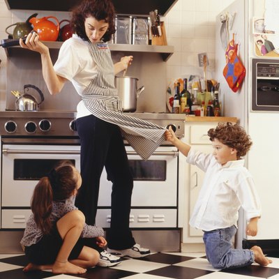 Two children (4-5) (6-7), seeking attention from mother in kitchen