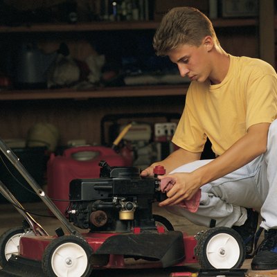 Teenage boy fixing lawnmower