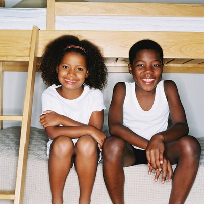 portrait of a young brother and sister sitting on a bed